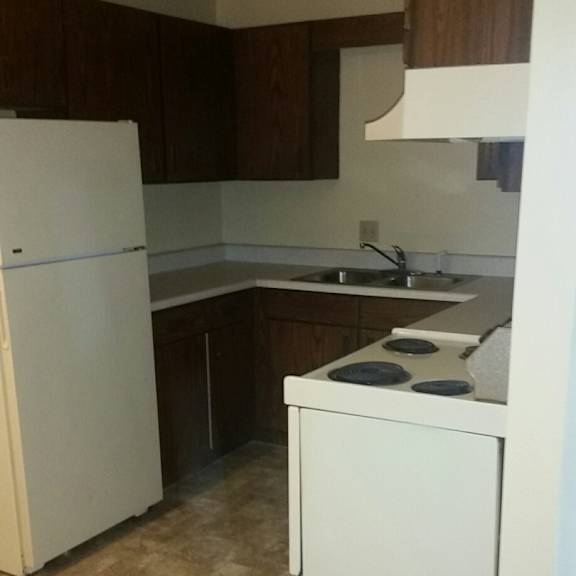 a kitchen with a white refrigerator and brown cabinets.