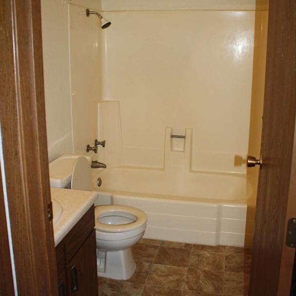 a white toilet is in a bathroom with a white tub and sink.