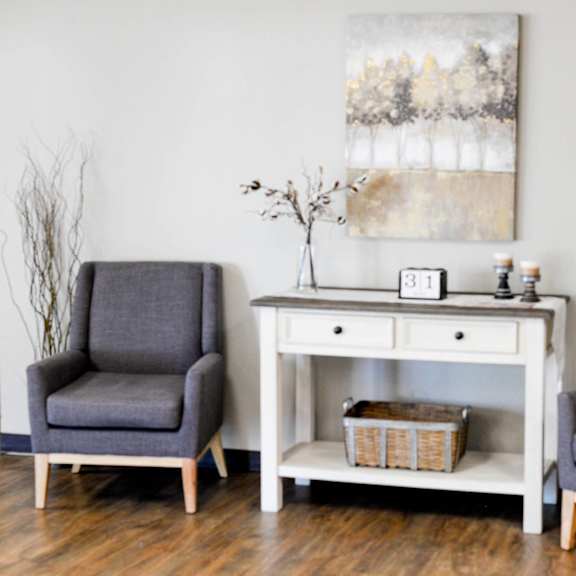 two grey chairs are placed in front of a white desk with a painting on the wall.