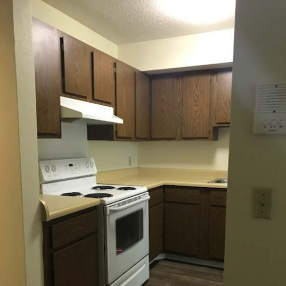 a kitchen with a white stove top oven and wooden cabinets.