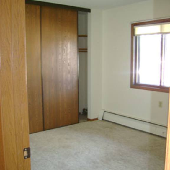 a room with a carpeted floor and a window with blinds.