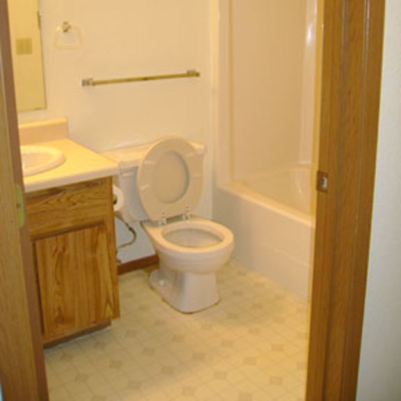 a white toilet in a bathroom with a white tiled floor.