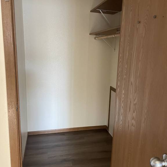 a white wall with a brown door and a shelf above it.