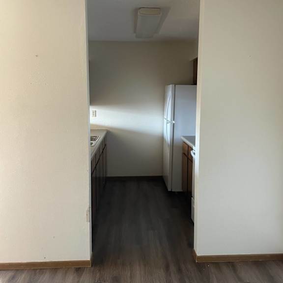 a kitchen with white cabinets and a wooden floor.