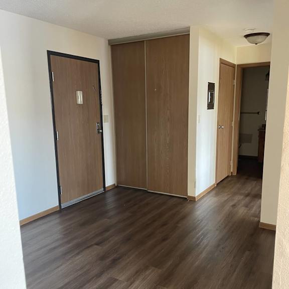 a hallway with two doors and a wooden floor.