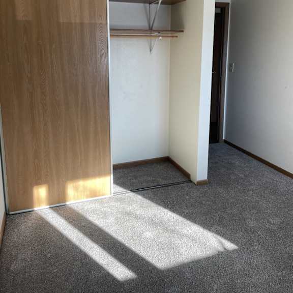 a room with a wooden door and a grey carpet.