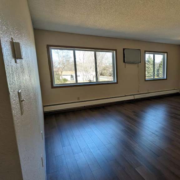 a room with wooden floors and two windows.