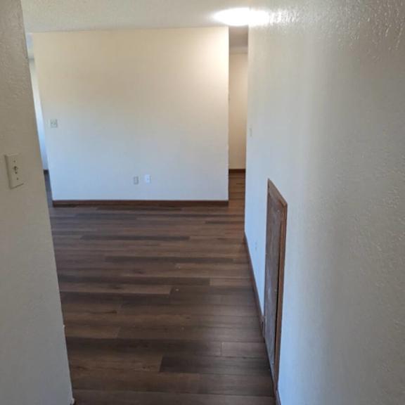 a long hallway with wood floors and white walls.