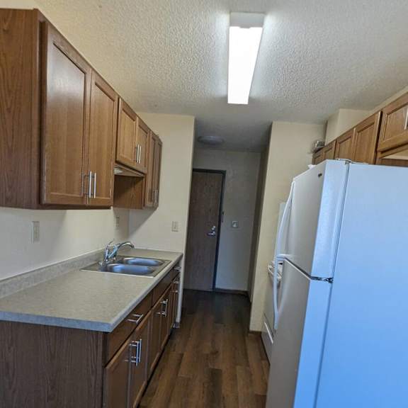 a kitchen with a white refrigerator and wooden cabinets.