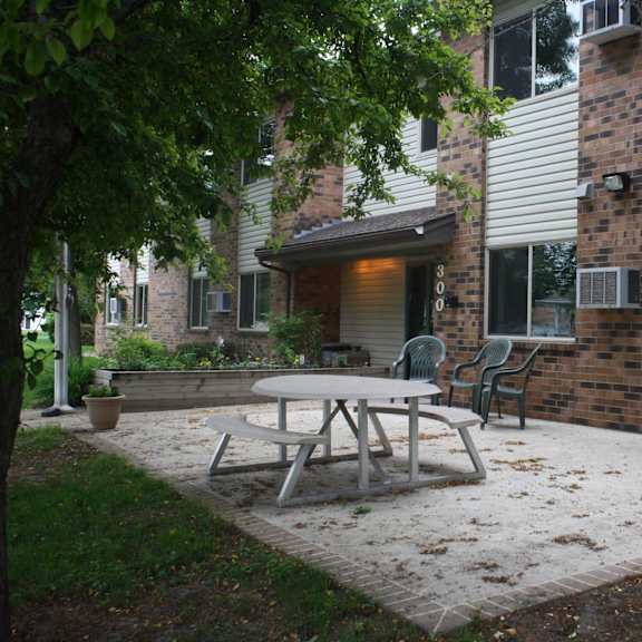 a patio with a table and chairs is surrounded by a brick building.