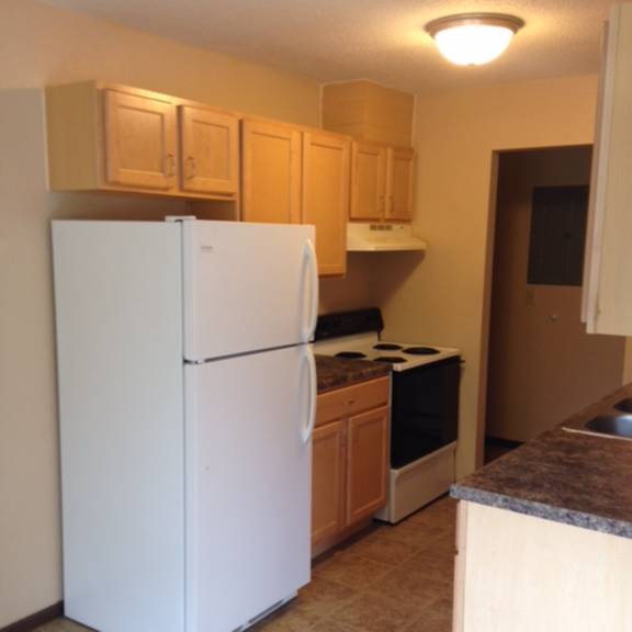 a white refrigerator in a kitchen with wooden cabinets.