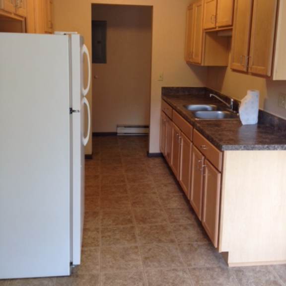 a kitchen with a white refrigerator and brown cabinets.