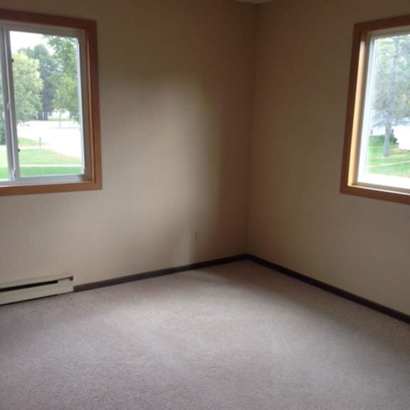 a room with a carpeted floor and two windows.