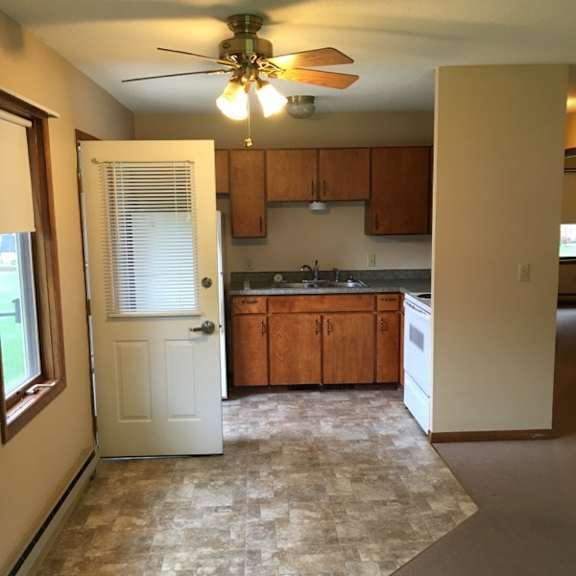 a kitchen with a white door and a fan on the ceiling.