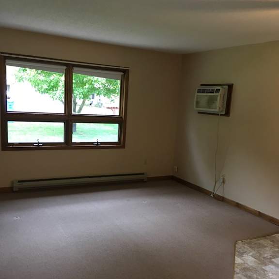 a room with a window and a wall-mounted air conditioner unit.