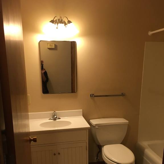 a bathroom with a toilet, sink, and mirror.