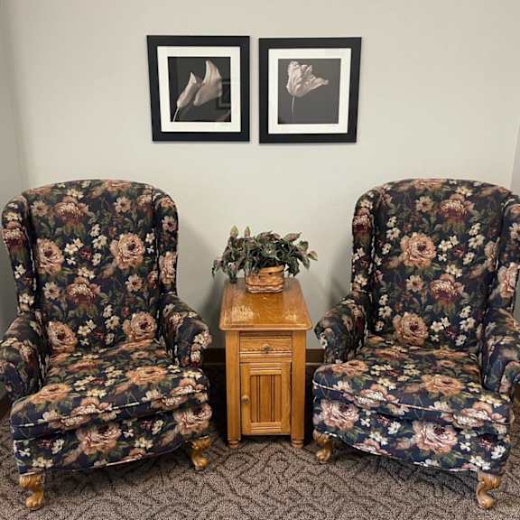 two floral chairs with a small wooden table between them.