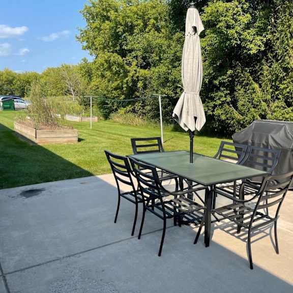 a table with chairs and an umbrella is set up on a patio.