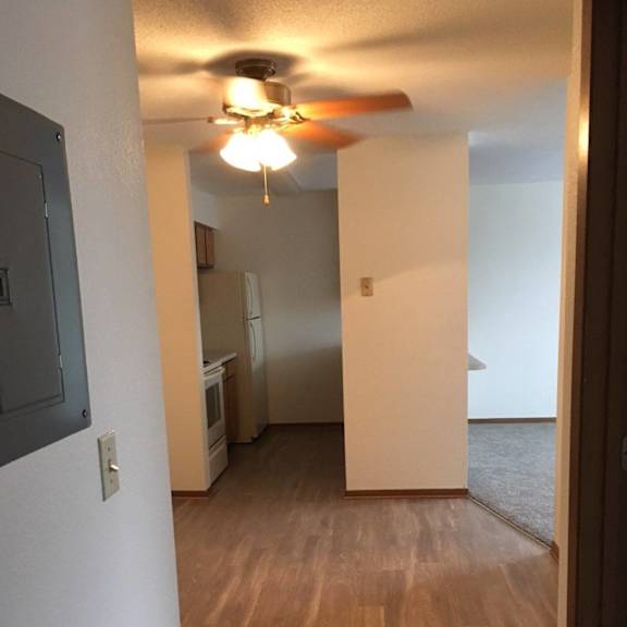 a room with a ceiling fan and wooden flooring.