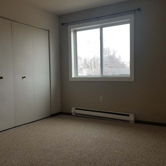 a room with a carpeted floor, a window, and a door.