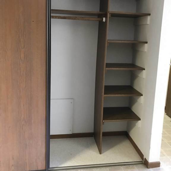 a tall wooden shelving unit with a sliding door.