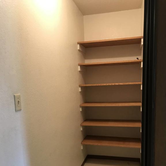 a white wall with a light switch and a shelf.