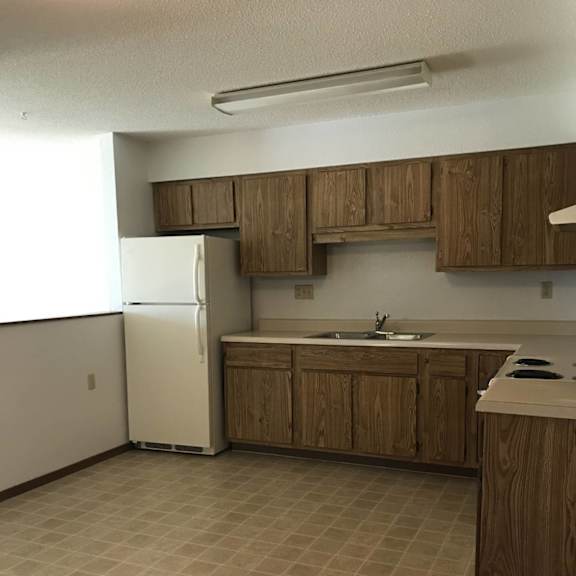 a kitchen with a white refrigerator and wooden cabinets.
