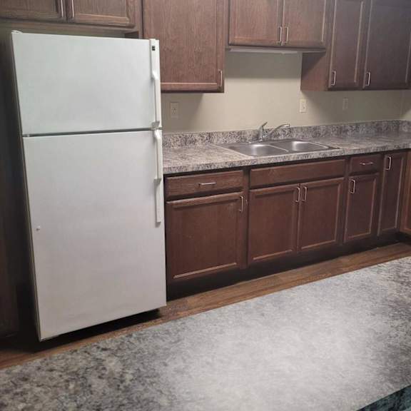 a white refrigerator in a kitchen with brown cabinets.