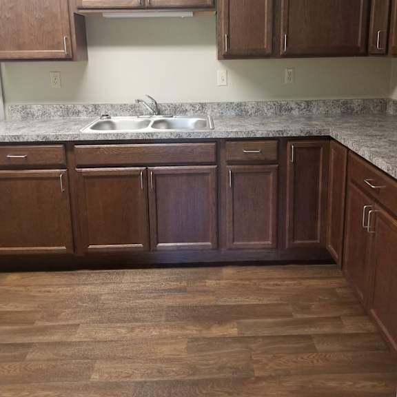 a kitchen with wooden cabinets and a marble countertop.