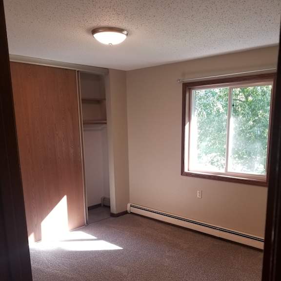 a room with a carpeted floor, a window, and a door.