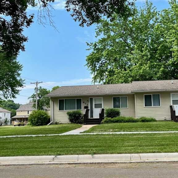 a house with a green lawn and trees in the background.