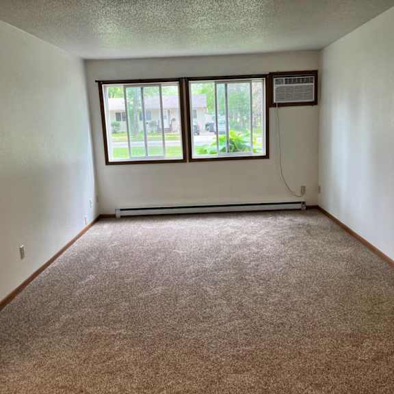 a room with a carpeted floor and a window overlooking a parking lot.