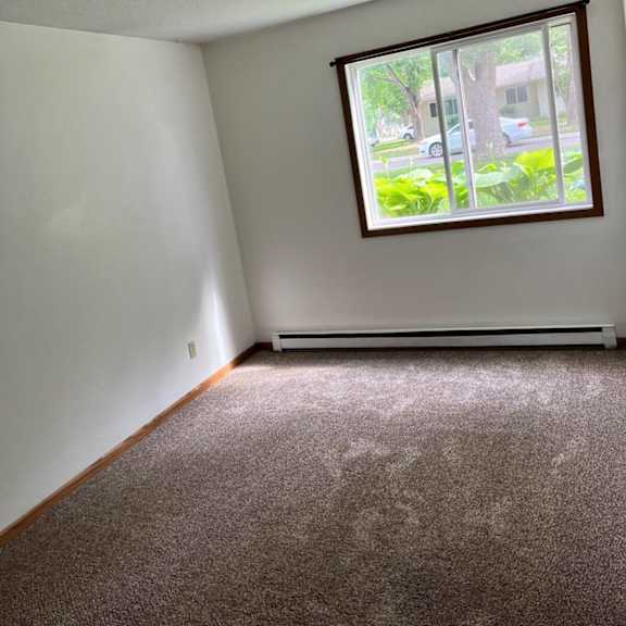 a room with a window and a carpeted floor.