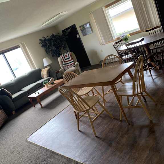a living room with a grey couch, wooden chairs and a dining table.