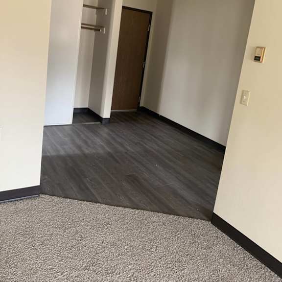 a hallway with a brown door and a light switch on the wall.