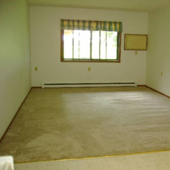 a room with a window and a rug on the floor.