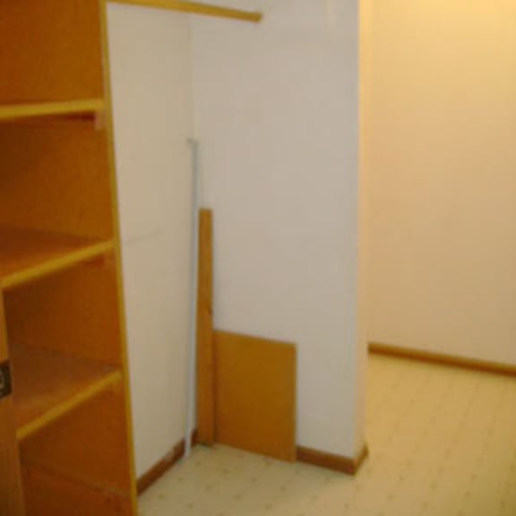a room with a white wall and a wooden shelf.