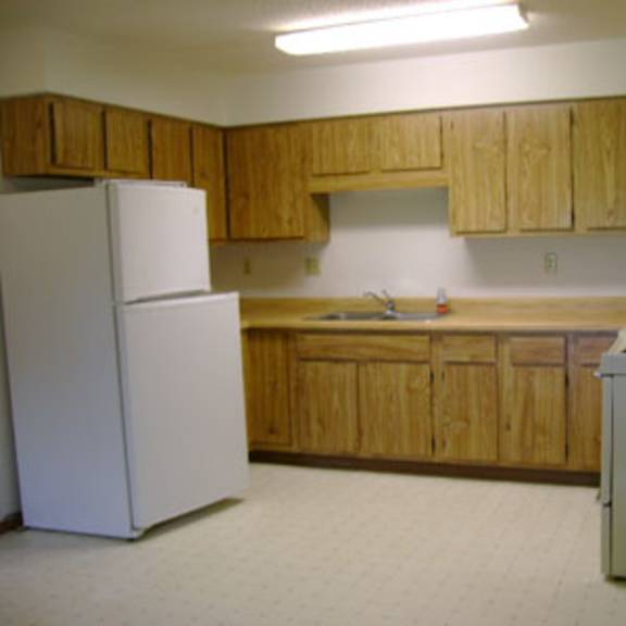 a white refrigerator stands in a kitchen with wooden cabinets.
