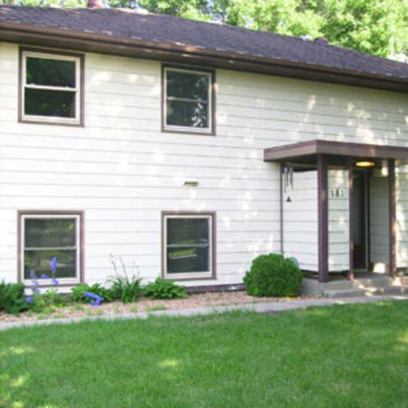 a white house with a brown roof and a small front yard.