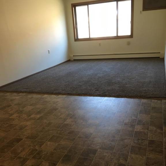 a room with a brown tiled floor and a window letting in sunlight.
