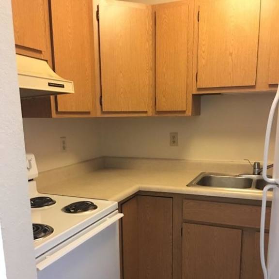 a kitchen with white appliances and wooden cabinets.