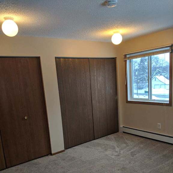 a room with two brown doors and a window.