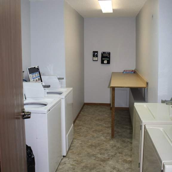 a small room with a washer and dryer and a table.