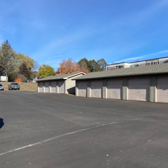 a parking lot with a building and a tree in the background.