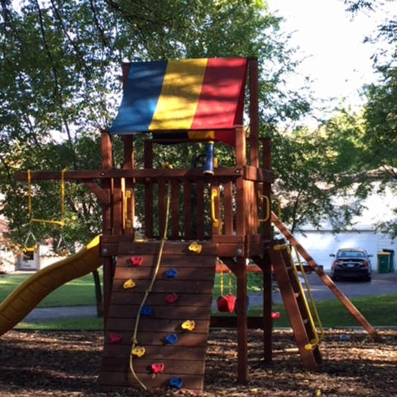 a wooden playground structure with a slide and climbing wall.