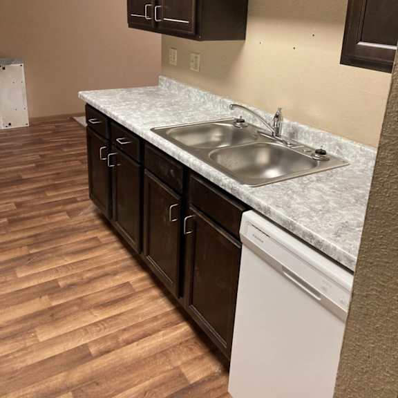 a kitchen with a white dishwasher and brown cabinets.
