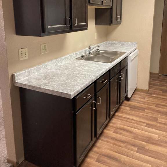 a kitchen with dark brown cabinets and a white counter top.