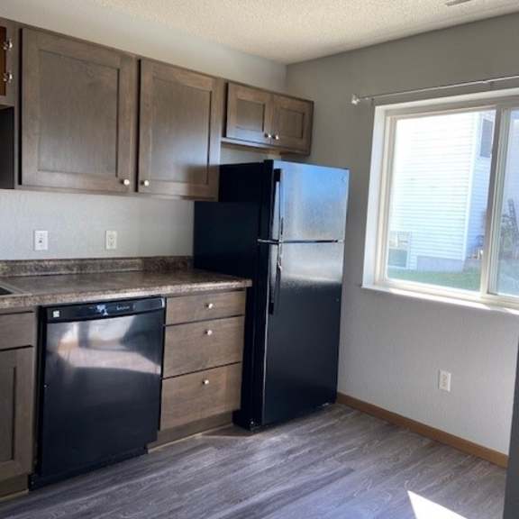 a kitchen with a black refrigerator and a dishwasher.