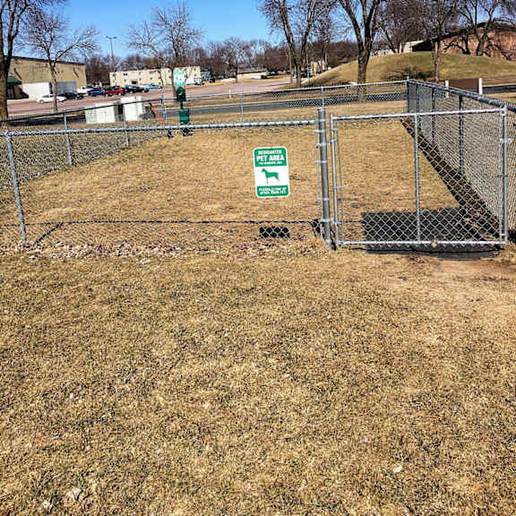 a green sign is attached to a fence in a field.