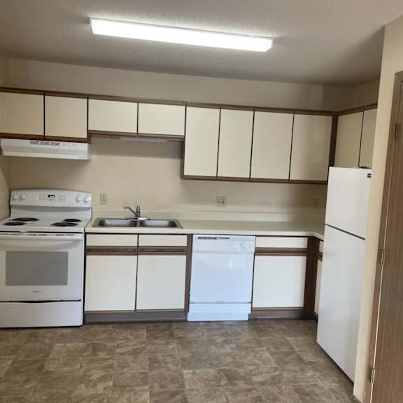 a kitchen with white appliances and brown cabinets.